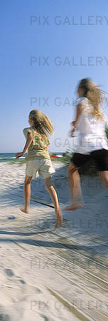 Flickor springer på strand