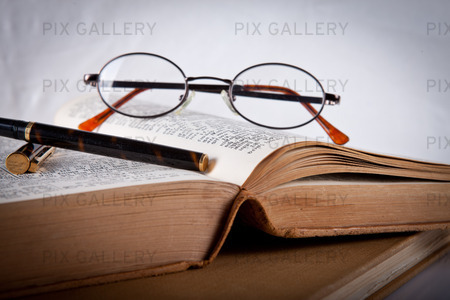 Läsglasögon och en penna om på en bok