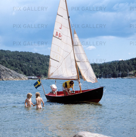 Barn som badar vid segelbåt