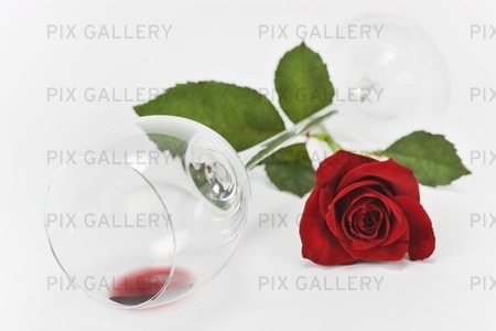 Röd ros vid liggande vinglas