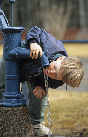Pojke som dricker ur vattenpump