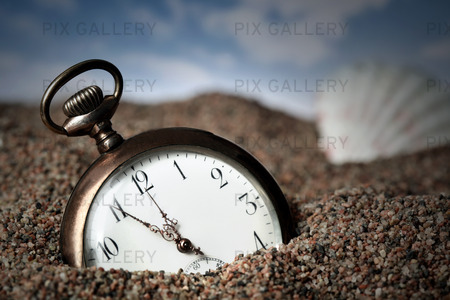 	Old pocket watch buried in sand