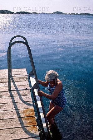Kvinna badar från brygga, Bohuslän