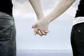 A couple holds hands in front of the sea