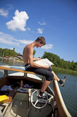 Pojke styr motorbåt med foten