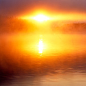 Soluppgång i dimma vid sjö