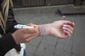 Tonåring skriver telefonnummer på armen